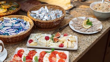 Una mesa de buffet con varios quesos, frutas y un tazón de ensalada.