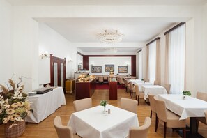 A hotel dining room with multiple tables, a buffet area, and artwork on the walls. - Grandhotel Havel (Jihlava)