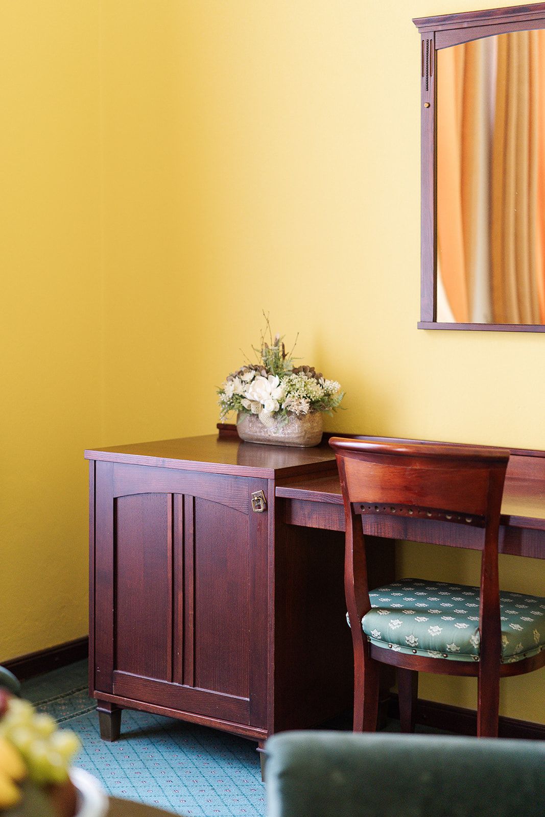 Un comedor con una mesa y sillas de madera, una planta en maceta sobre la mesa y un espejo en la pared.