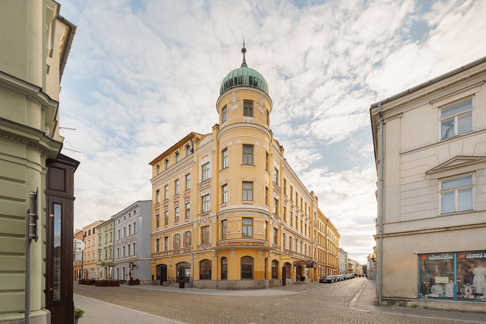 Ein historisches Gebäude mit einer markanten Kuppel und klassischer Architektur, gelegen in einer Kopfsteinpflasterstraße.