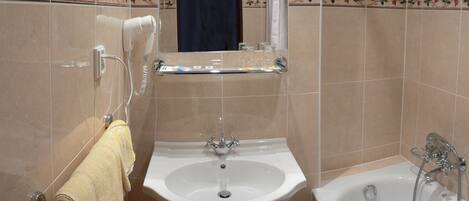 Un baño con lavabo, espejo, secador de pelo y bañera.