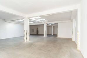 A spacious, empty interior with white walls, concrete floors, and multiple ceiling lights. - Grandhotel Havel (Jihlava)