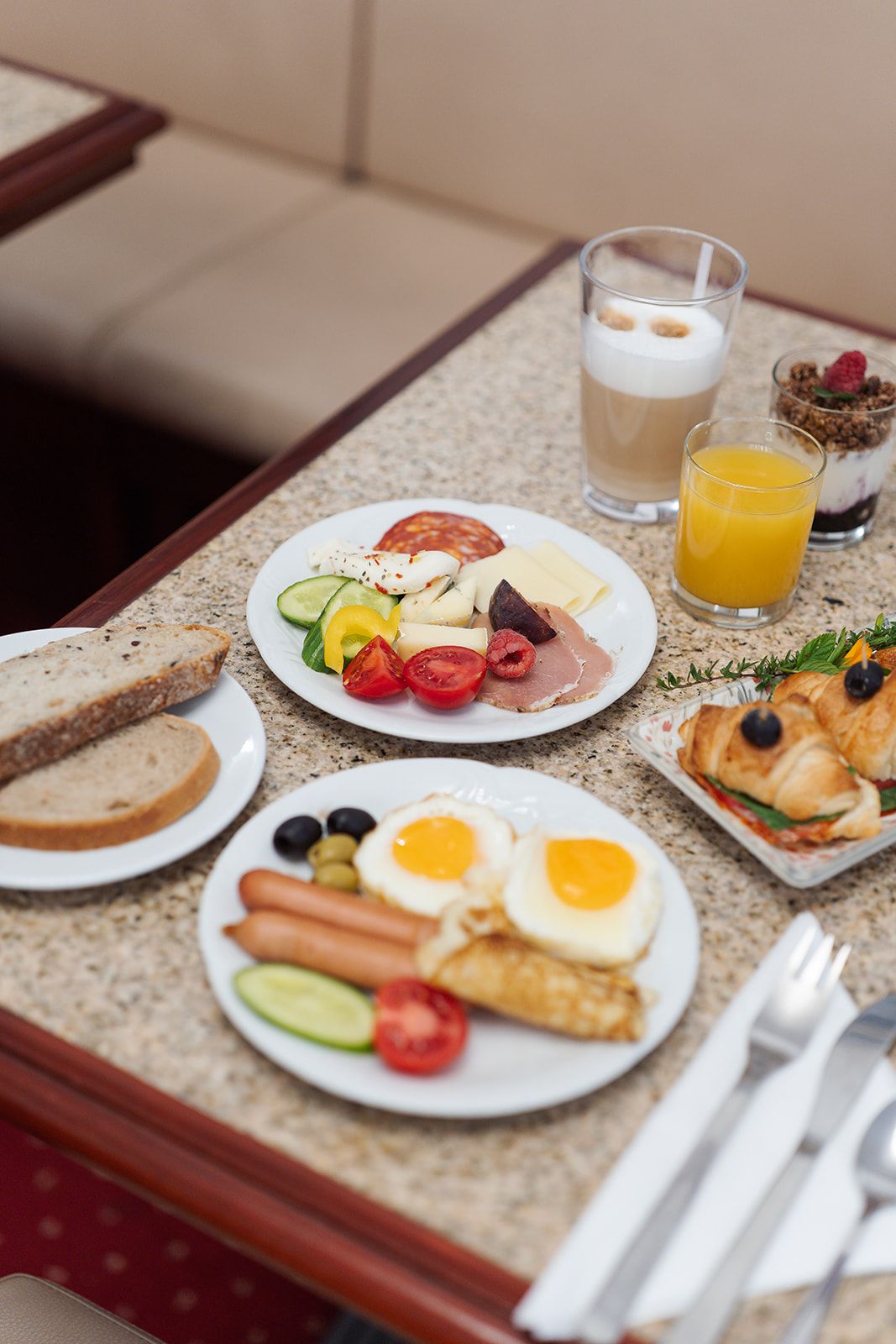 A breakfast setting with plates of food, a glass of orange juice, and a glass of milk.