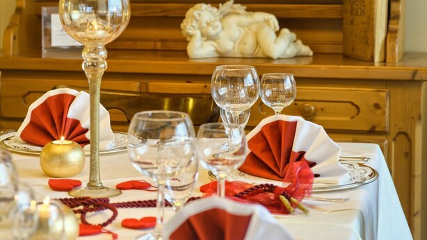 A table set with wine glasses, a candle, and red and white napkins.