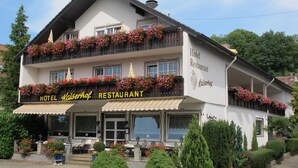 A two-story hotel with a restaurant on the ground floor, featuring balconies with flower boxes and a sign that reads "Hotel Restaurant Kaiserhof."