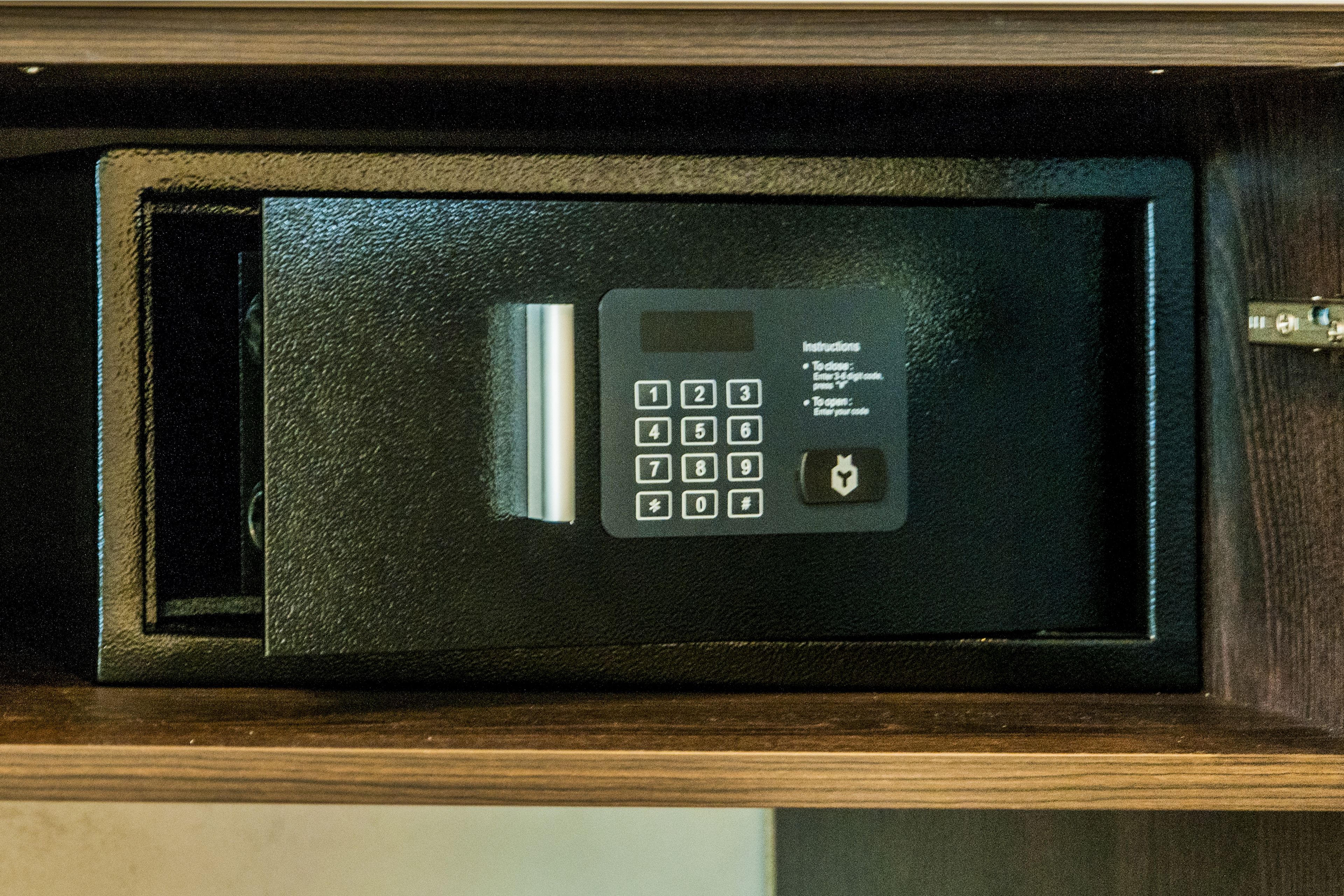 Un microondas negro con teclado y manual de instrucciones sobre un mueble de madera.