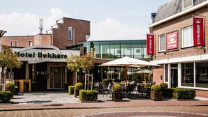 A hotel with a modern entrance, outdoor seating area, and visible signage for a steakhouse. - Dekkers Hotel (Ossendrecht)
