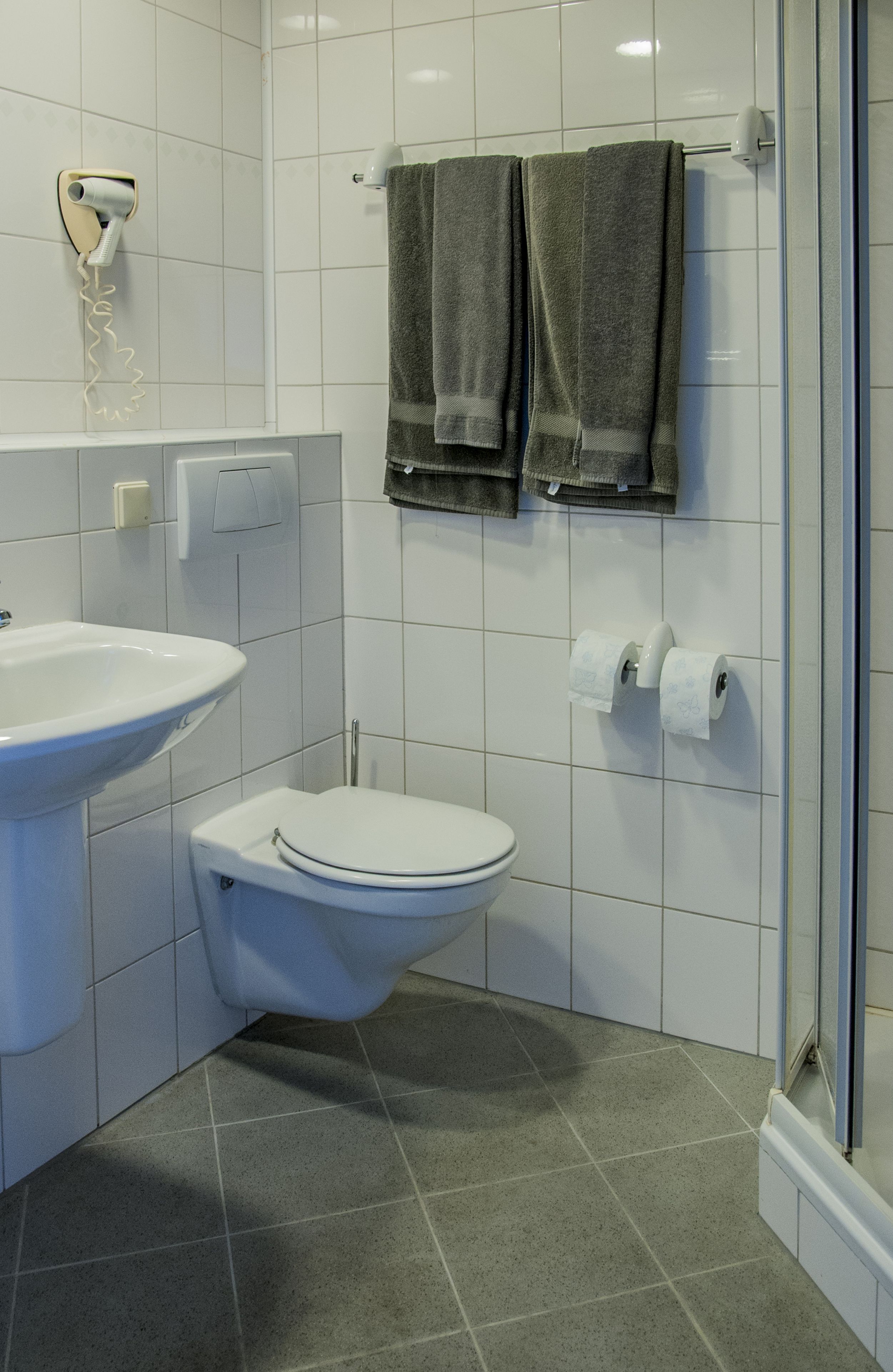 Un bagno con lavandino bianco, servizi igienici e cabina doccia in vetro.