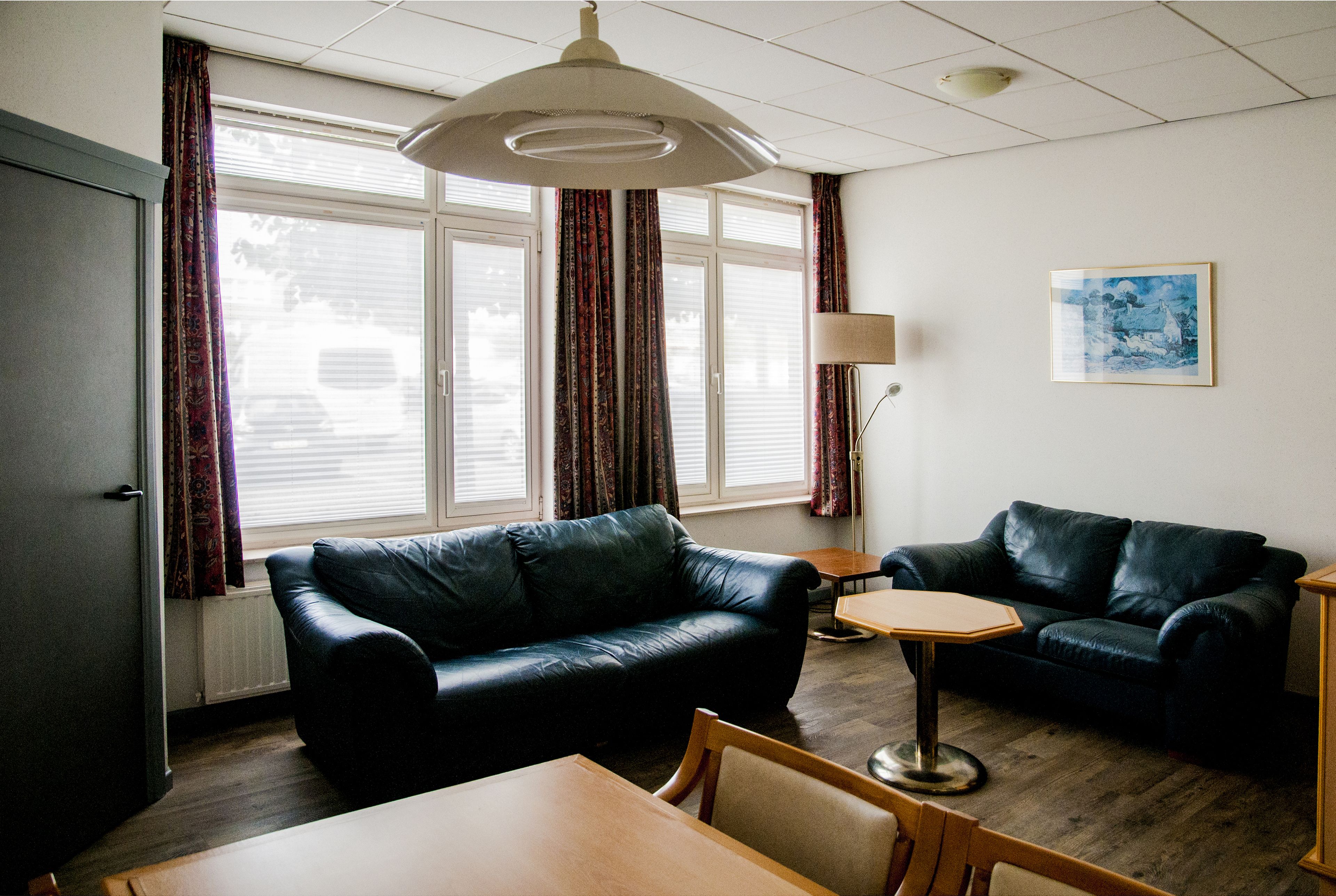 A living room with two black leather sofas, a wooden table, and a lamp.
