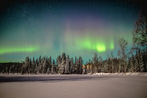 Un paisaje nevado con cielo nocturno despejado y aurora boreal visible.