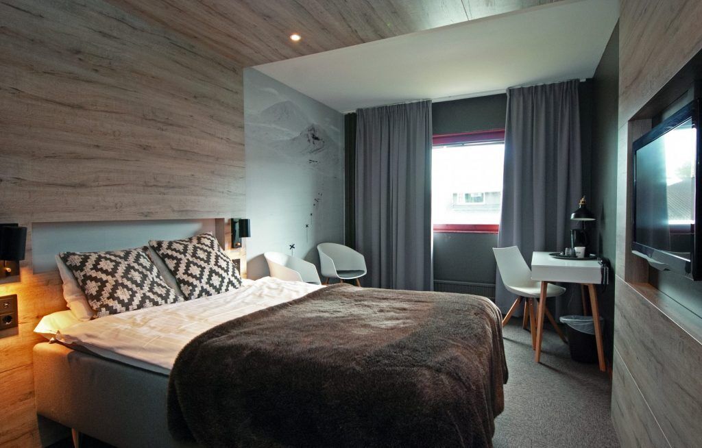 Une chambre d’hôtel moderne équipée d’un lit, d’un bureau, d’une chaise et d’un téléviseur.