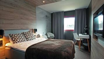 Une chambre d’hôtel moderne équipée d’un lit, d’un bureau, d’une chaise et d’un téléviseur.