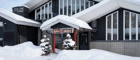Un edificio con letrero de pub y bistró, rodeado de nieve.