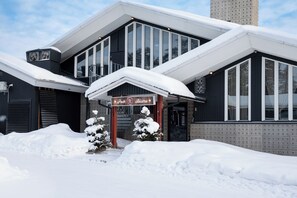 A building with a sign for a pub and bistro, surrounded by snow. - Hotell Laponia (Arvidsjaur)