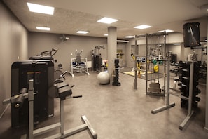 Un gimnasio con diversos equipos de ejercicio, que incluyen máquinas de pesas, una bicicleta estática y una máquina de remo.