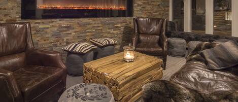 Una sala de estar acogedora con muebles de cuero, una pared de piedra y una chimenea.