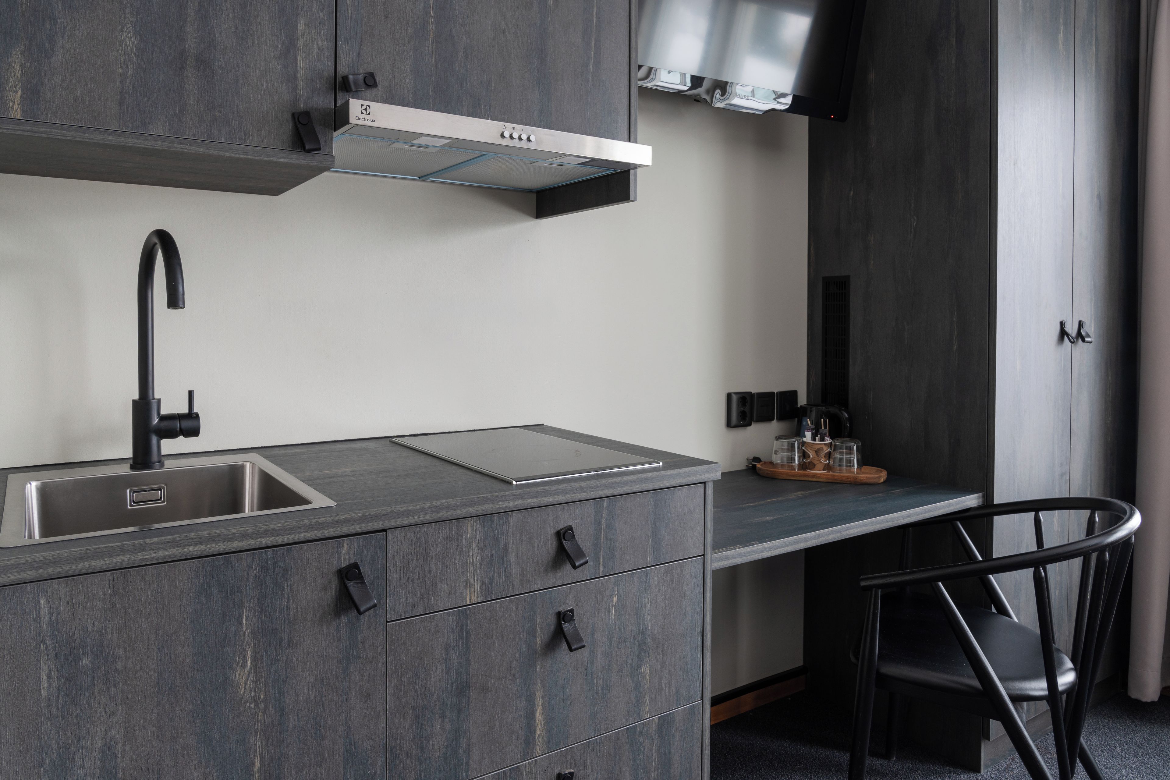 A modern kitchen with a built-in sink, a range hood, and a countertop with a glass-top stove.