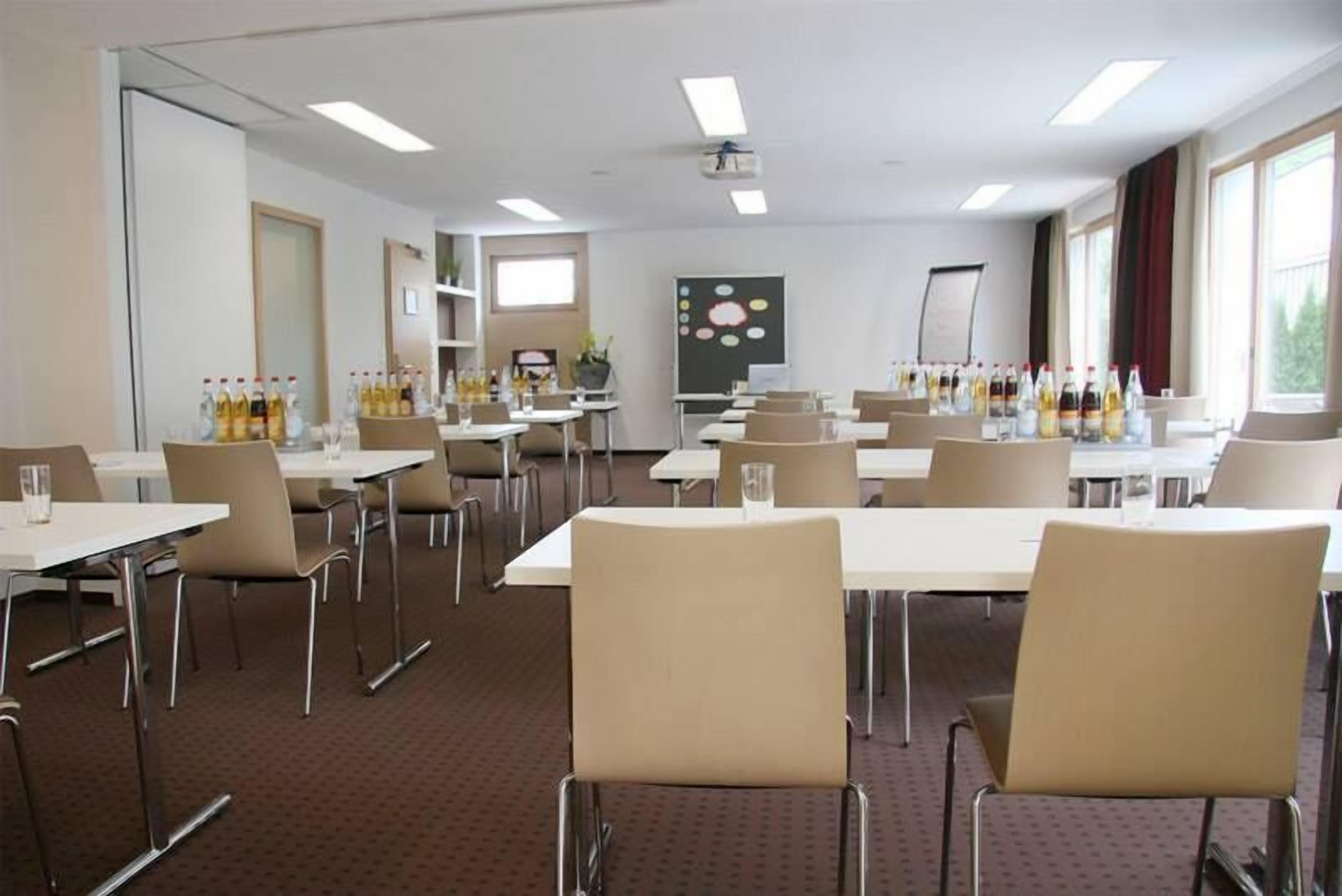 A conference room with tables, chairs, and a projector screen.