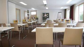 A conference room with tables, chairs, and a projector screen.