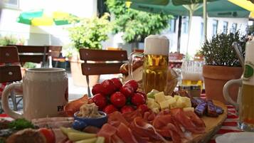 A charcuterie board with various meats, cheeses, and fruits, accompanied by beer mugs and a glass of beer.