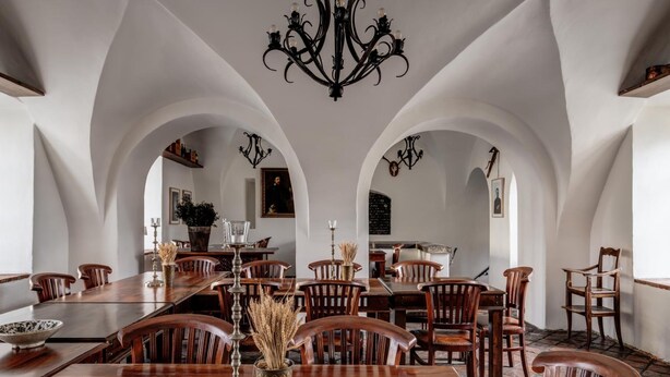 A dining area with a long wooden table, multiple chairs, and a chandelier. - Zamek Zabreh (Ostrava)