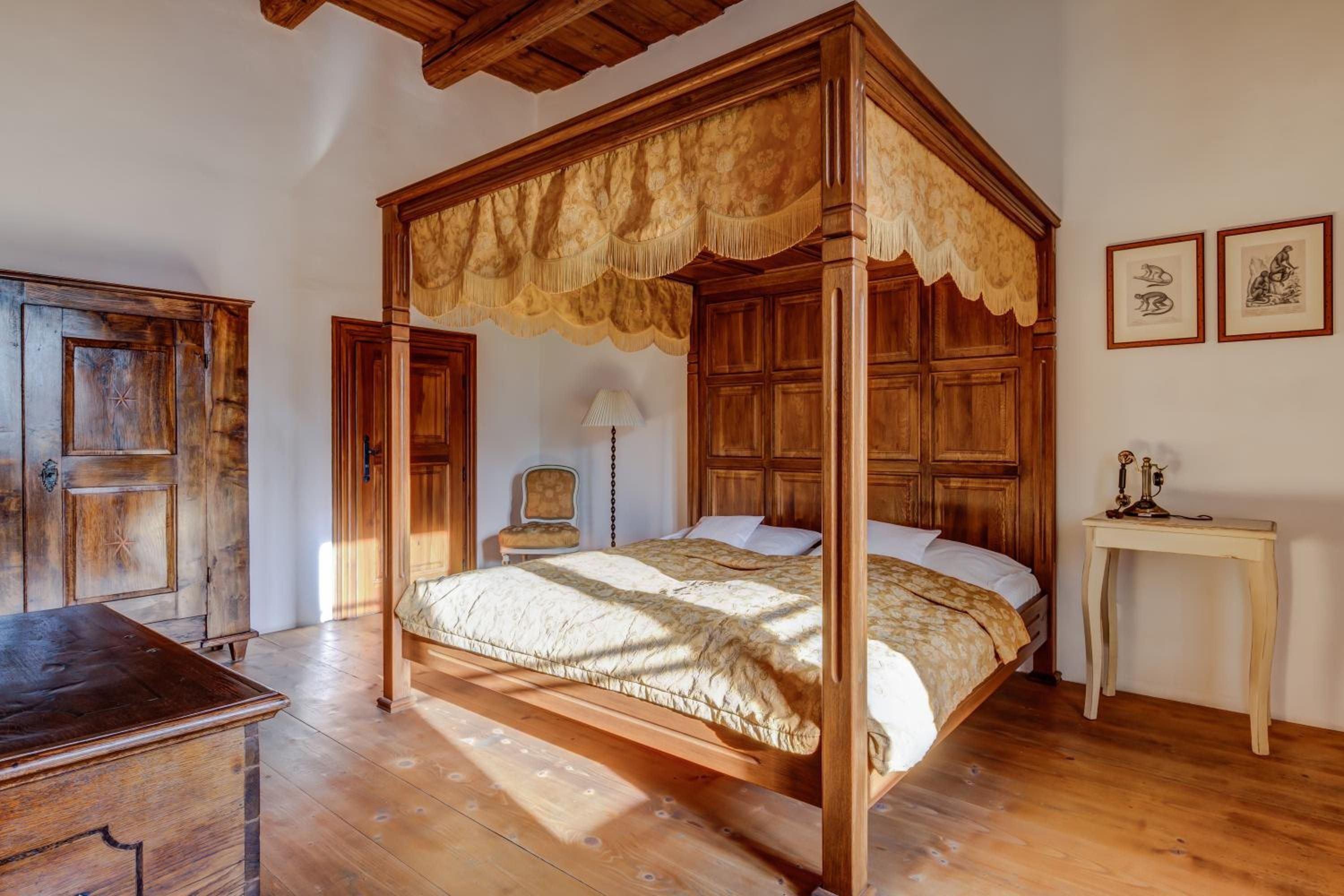 Een hemelbed met baldakijn, houten vloeren, een bureau en een stoel.