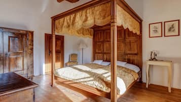Ein Himmelbett mit Baldachin, Holzboden, ein Schreibtisch und ein Stuhl.
