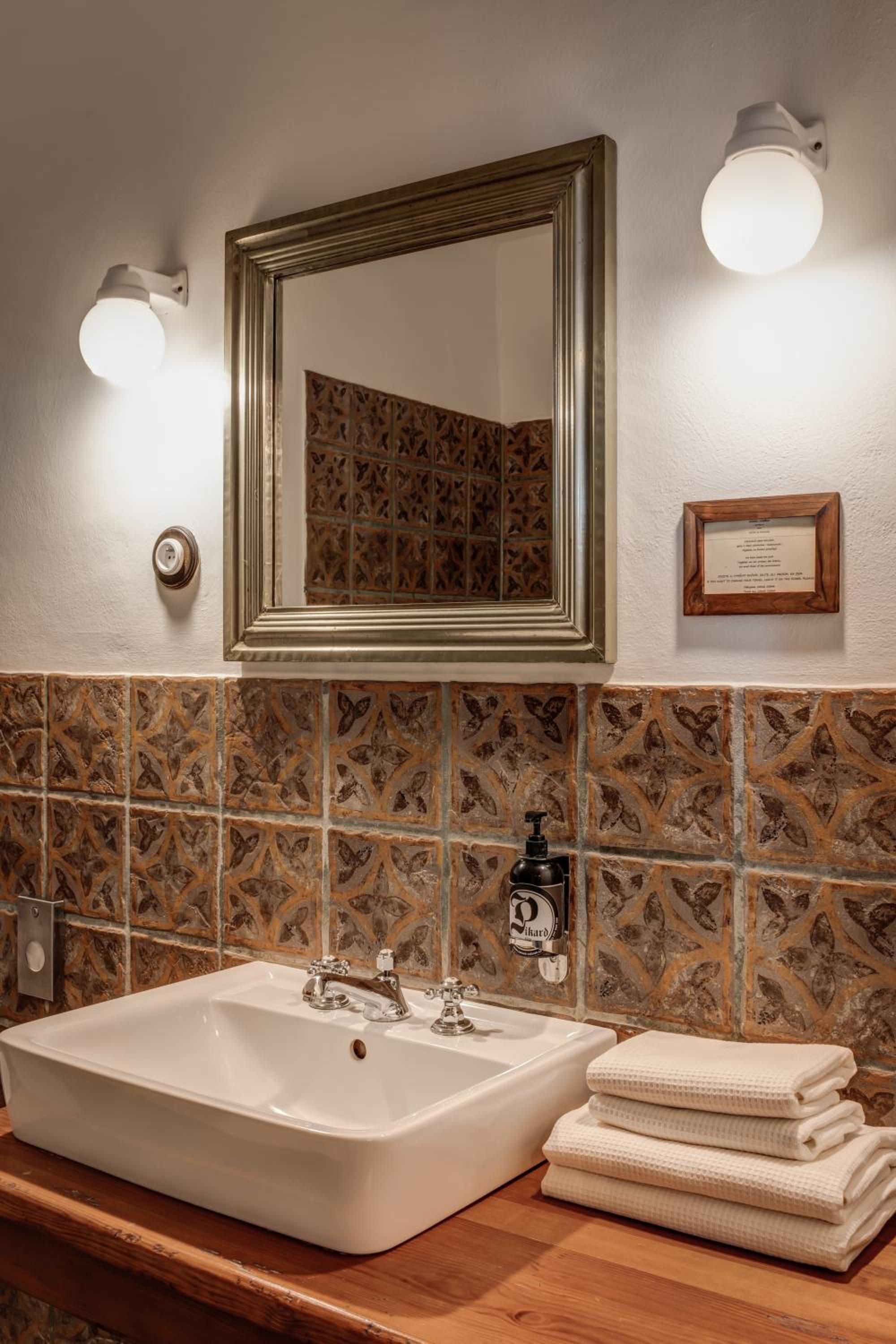 A bathroom with a large mirror, a sink, and a towel stack.