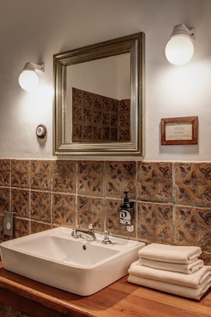 Un baño con un espejo grande, un lavabo y una pila de toallas.