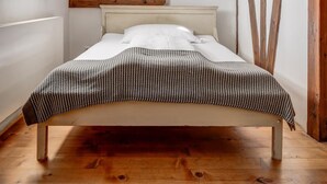 A bedroom with a sloped ceiling, a wooden bed frame, and a skylight. - Zamek Zabreh (Ostrava)