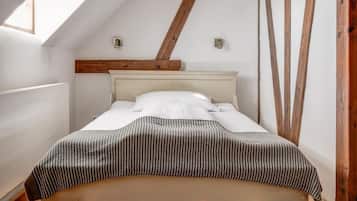 Un dormitorio con techo inclinado, estructura de cama de madera y tragaluz.
