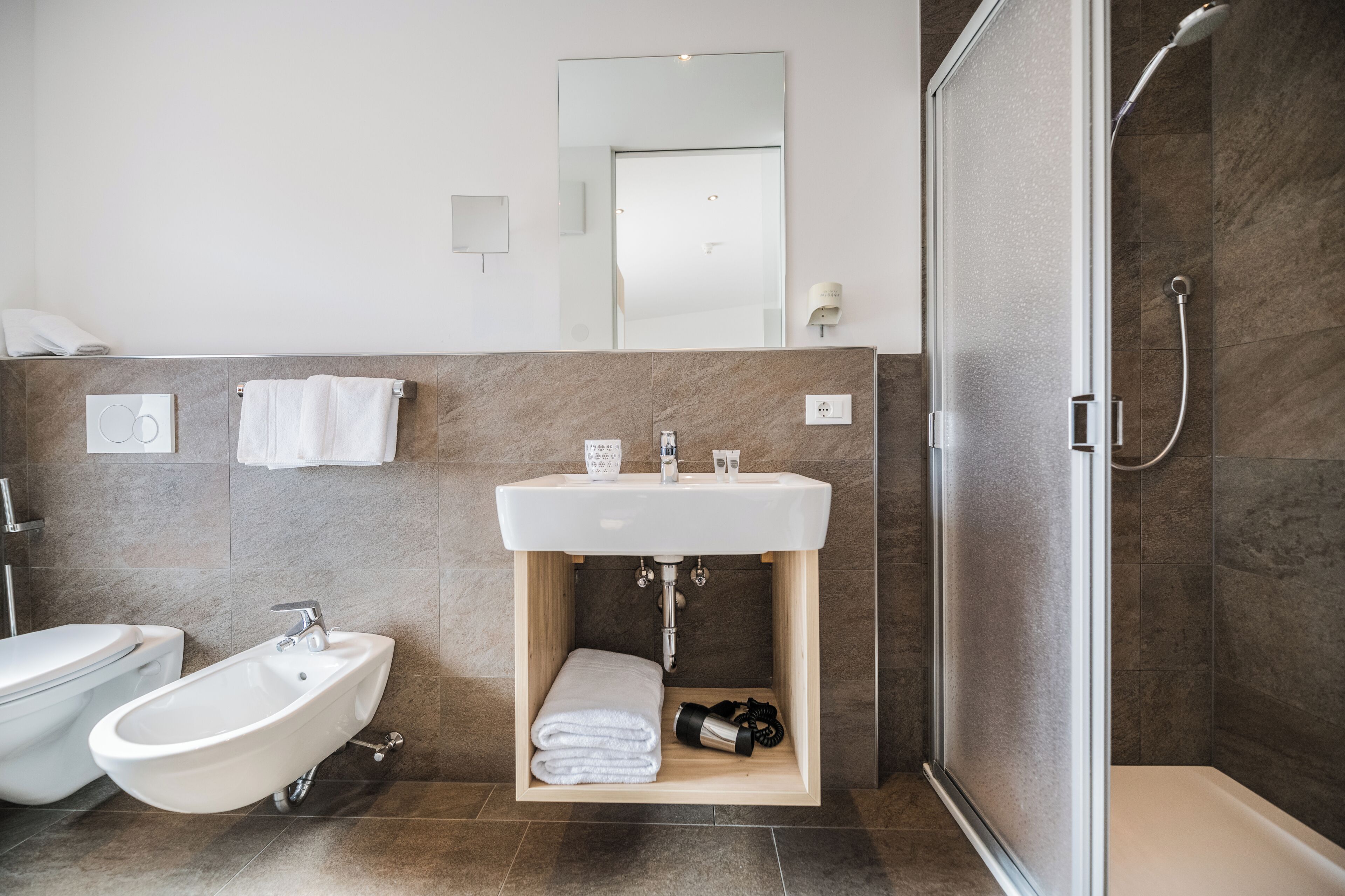 A modern bathroom with a sink, bidet, and shower.
