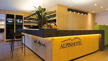 Un comptoir d’accueil avec un revêtement en bois, des tabourets de bar et un présentoir de fruits.