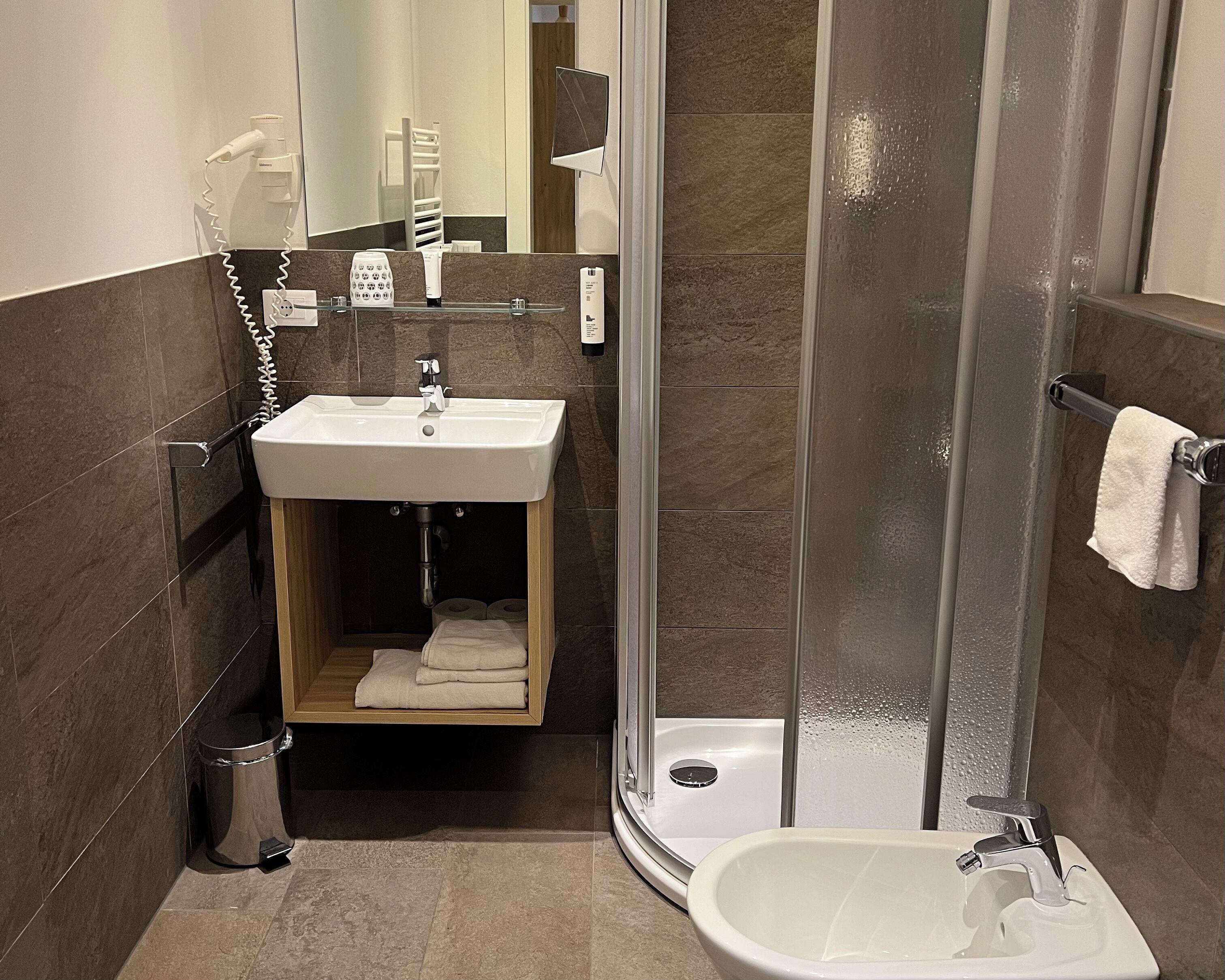 A modern bathroom with a shower, sink, and toilet.