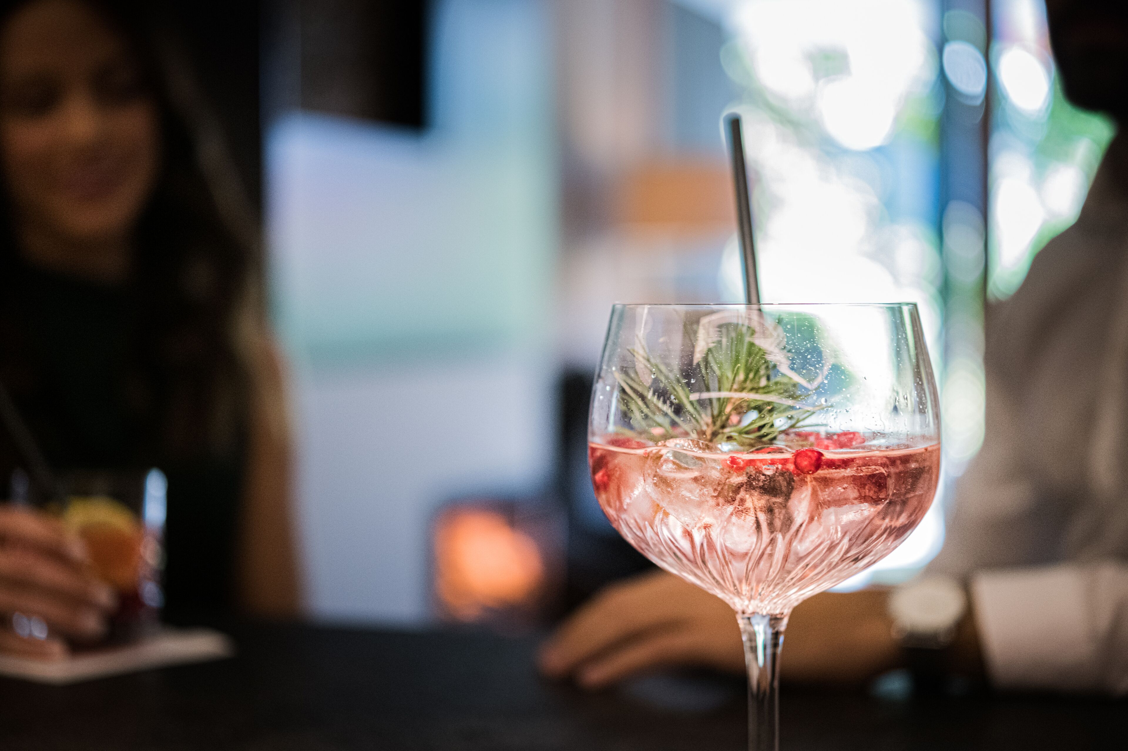 Un vaso de cóctel rosa con pajita y adorno, sobre una mesa.