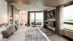 Une chambre d’hôtel moderne dotée d’un grand lit, d’une télévision, d’un balcon avec coin salon extérieur et offrant une vue sur l’extérieur.