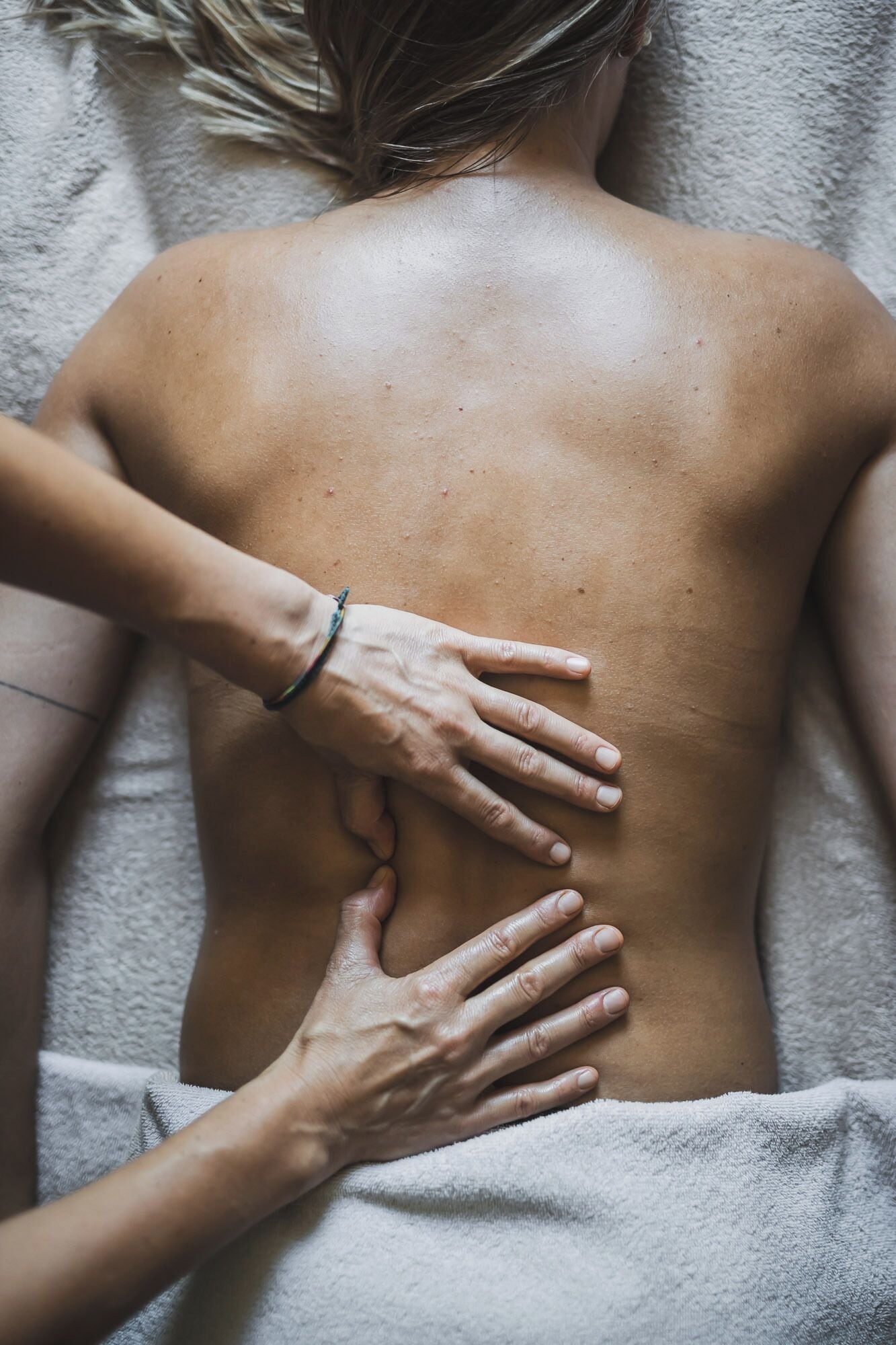 Eine Person bekommt eine Rückenmassage auf einem Handtuch.