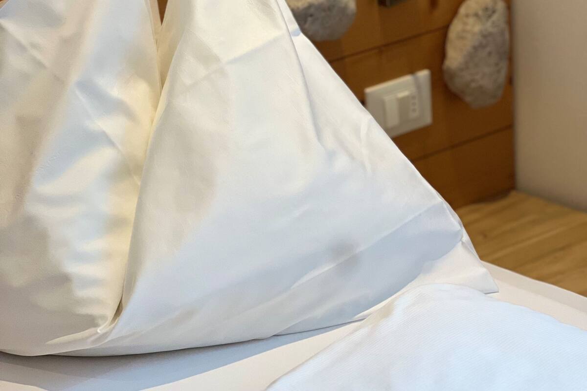 A bed with white bedding and a wooden headboard.