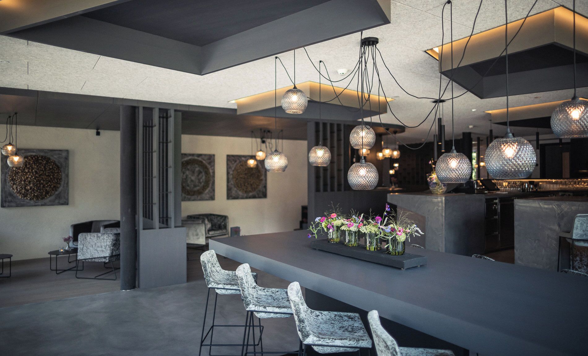 Une cuisine moderne dotée d’un îlot central, de luminaires suspendus et de sièges de bar.