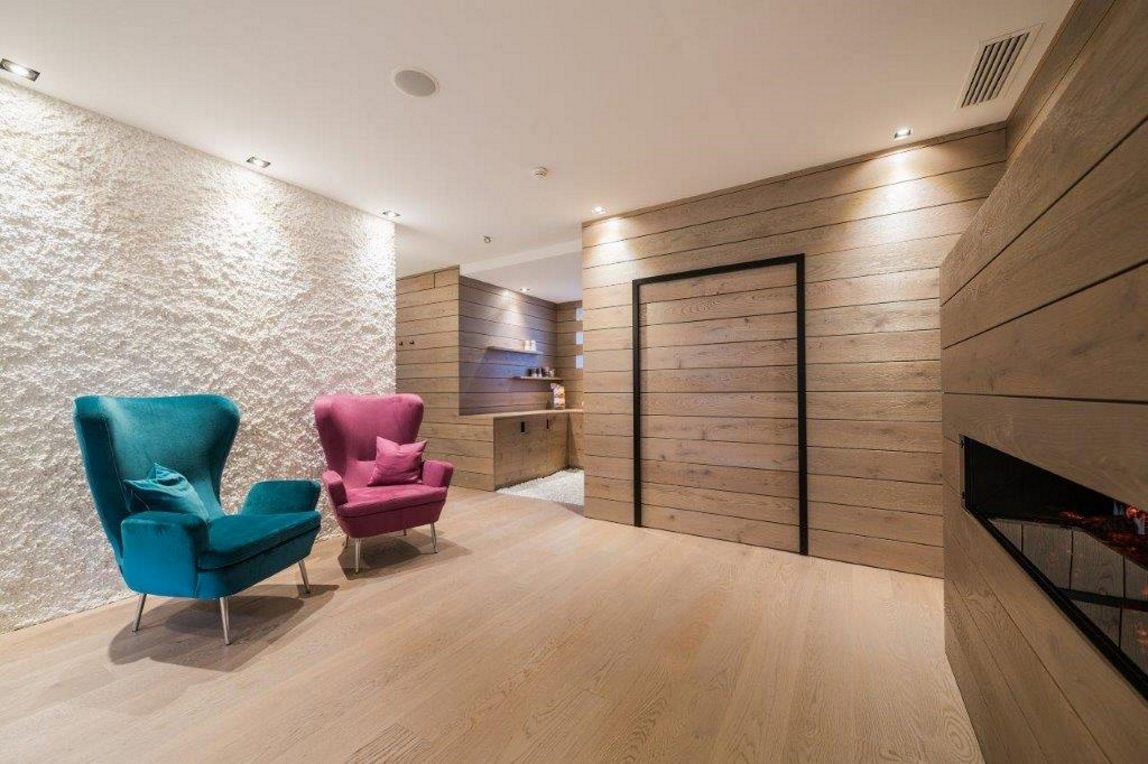 A modern interior with two armchairs, wooden panel walls, and a built-in shelf.