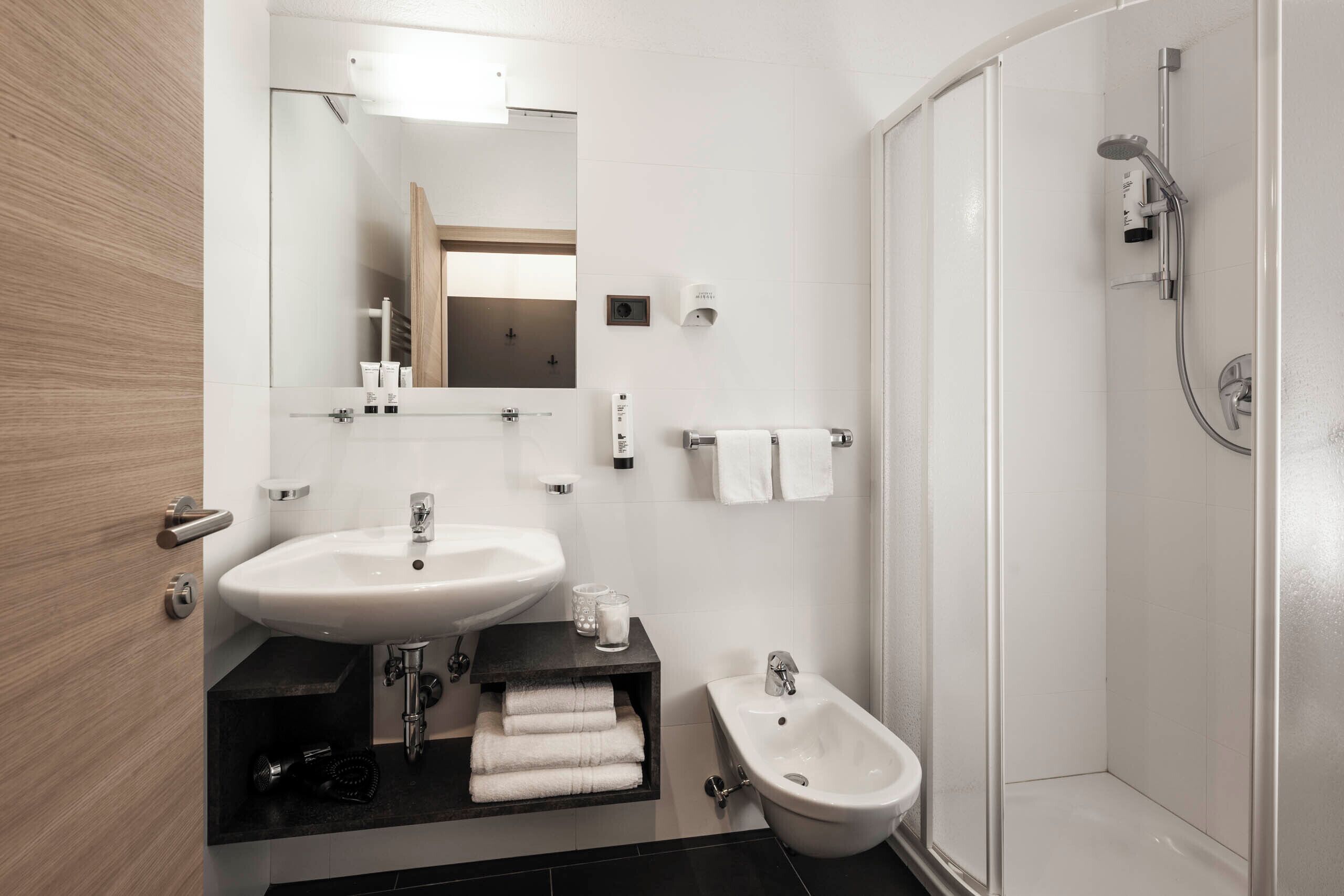 A modern bathroom with a sink, bidet, and shower.