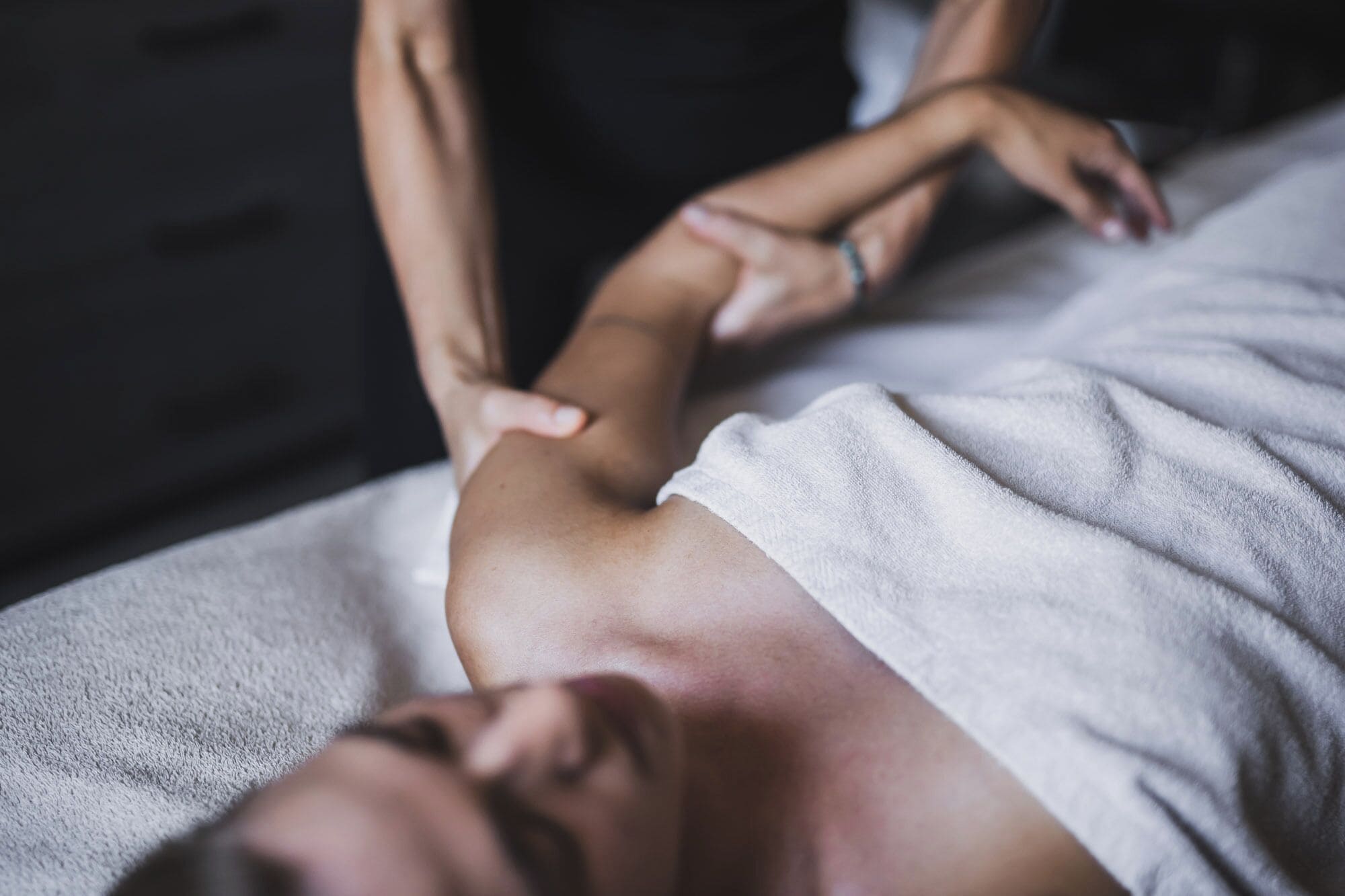 A person receiving a massage on a bed with a white towel.