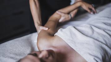 A person receiving a massage on a bed with a white towel.