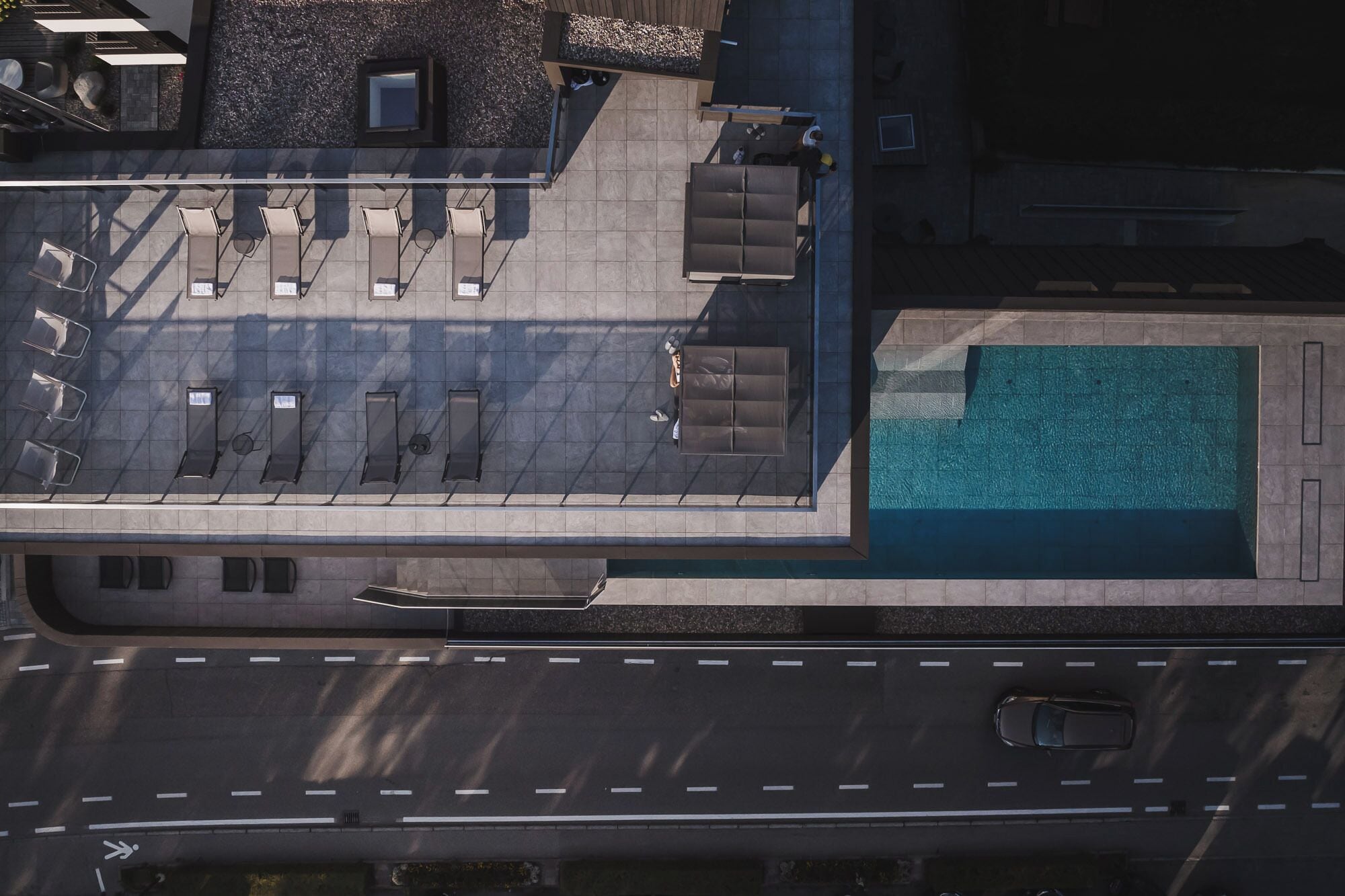 Vista aérea de la azotea de un hotel con piscina, tumbonas y una zona de estar cubierta.
