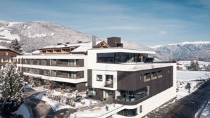Un hôtel moderne à plusieurs étages, doté de grandes fenêtres et offrant une vue sur les pistes de ski.