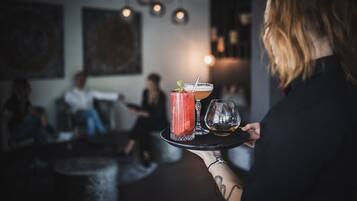 A person holding a tray with a cocktail, a glass of beer, and a margarita.