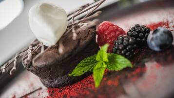 A dessert with chocolate cake, whipped cream, berries, and mint leaves.