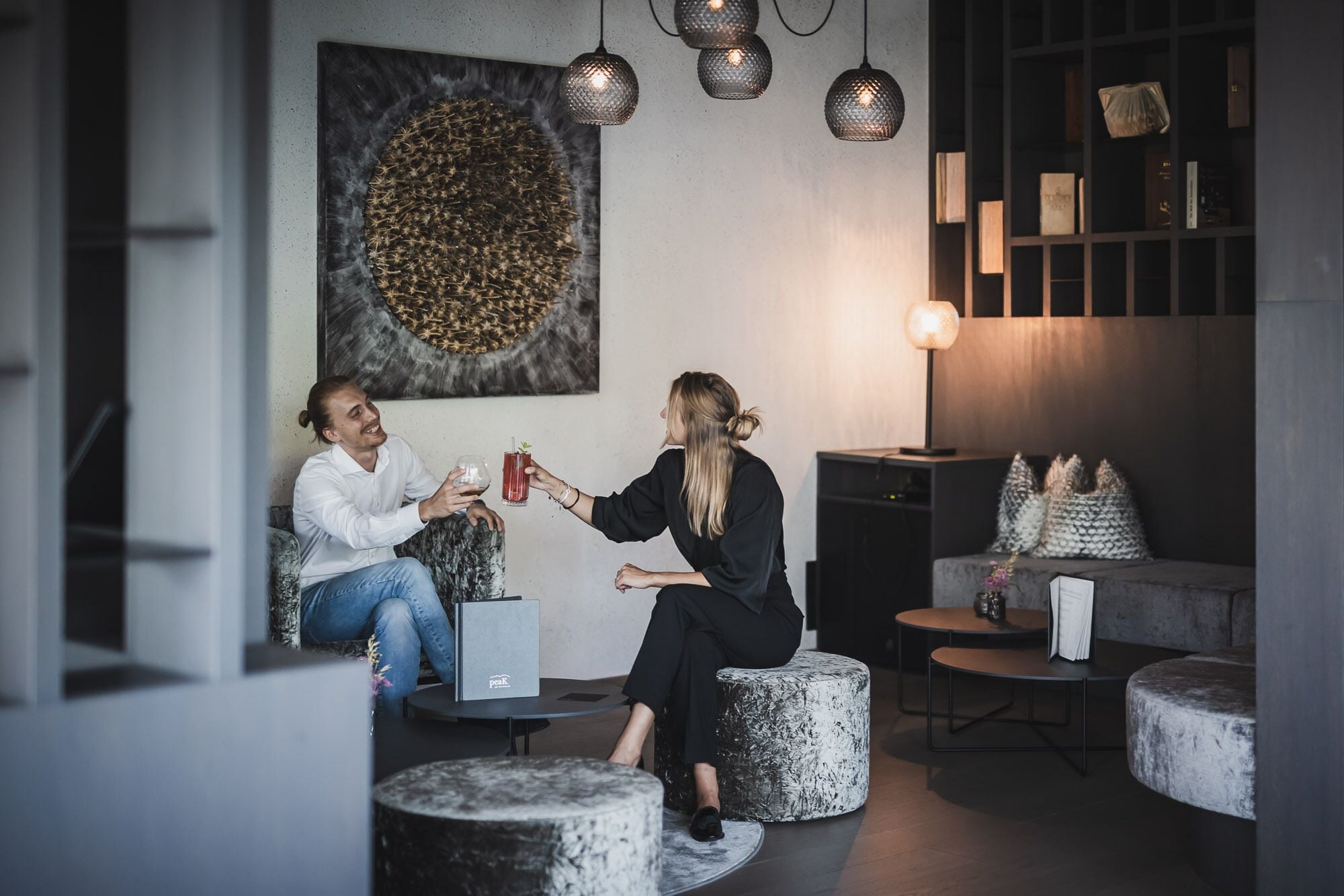 Un espace de détente moderne avec des sièges ronds, une grande peinture abstraite et des luminaires suspendus.