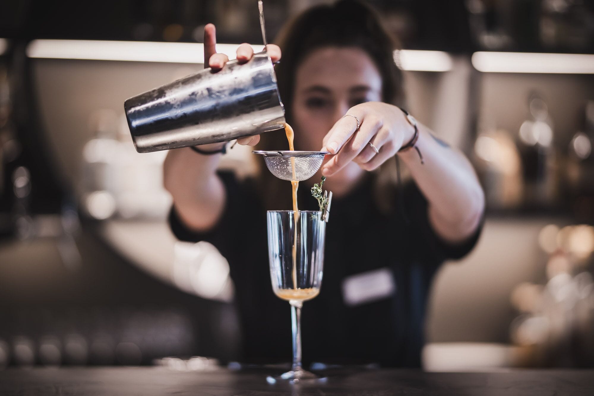 A bartender pouring a drink into a glass.