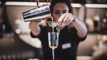 Ein Barkeeper gießt ein Getränk in ein Glas ein.